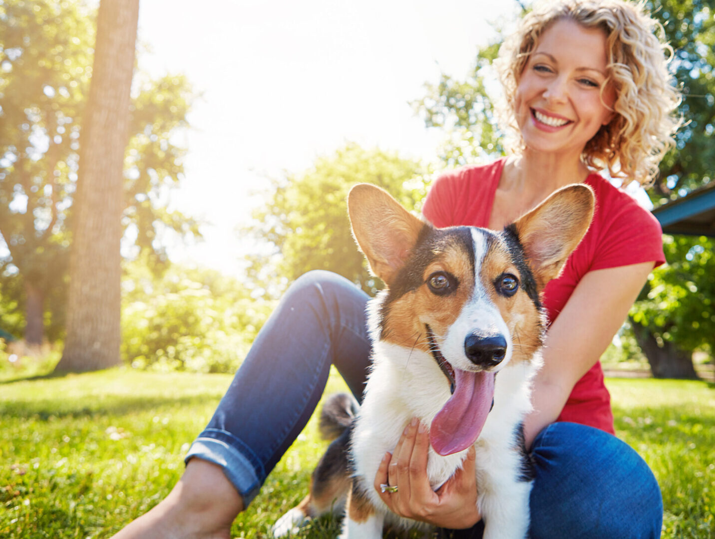 A woman sitting on the grass with her dog.