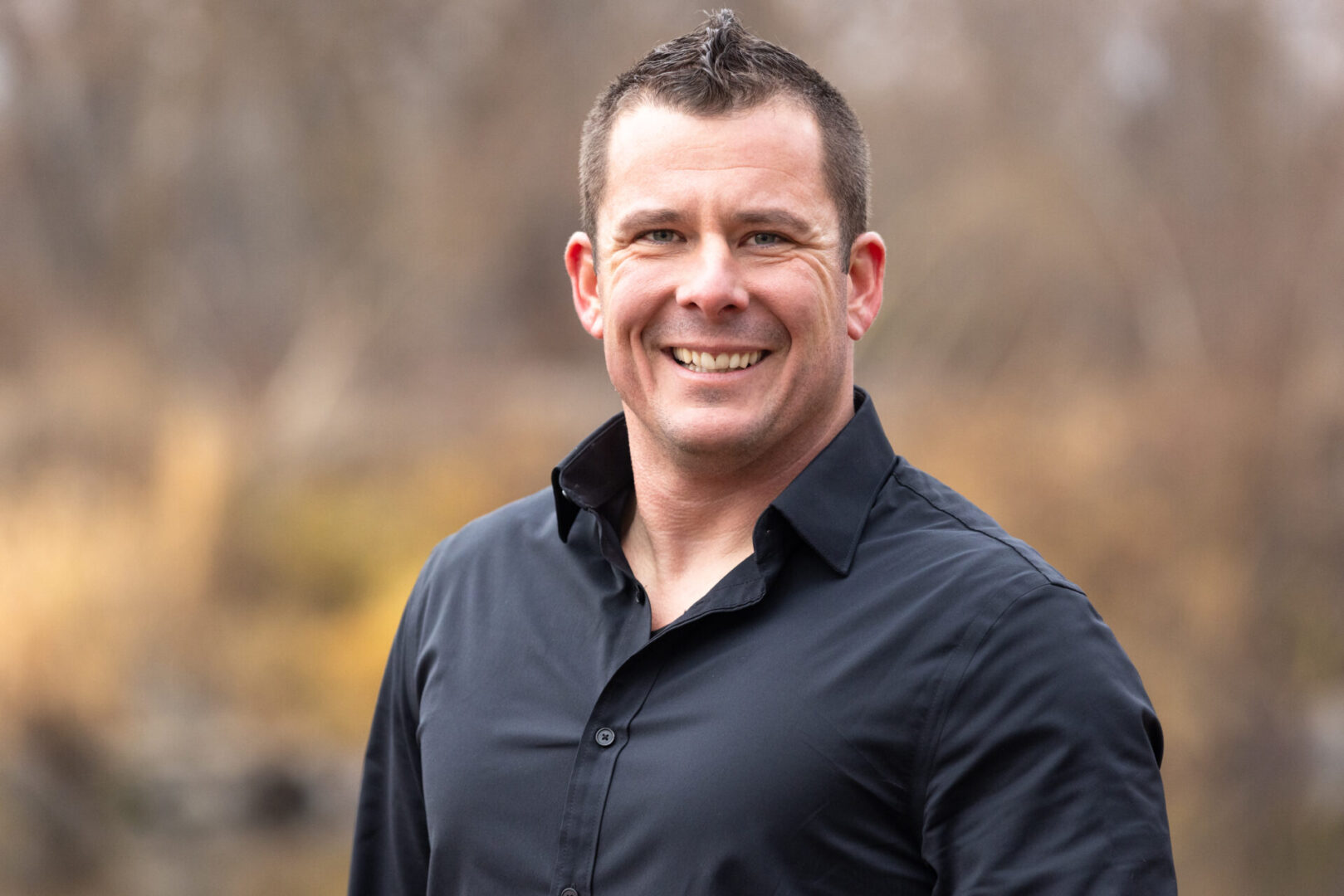 A man in black shirt smiling for the camera.